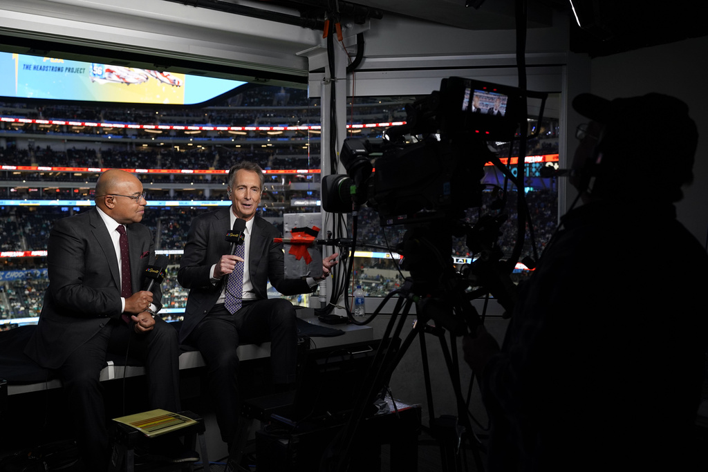 FILE - NBC Sports play-by-play announcer Mike Tirico, left, sits next to color commentator Cris Collinsworth before an NFL football game between the Los Angeles Chargers and the Miami Dolphins on Dec. 11, 2022, in Inglewood, Calif. (AP Photo/Jae C. Hong, File)