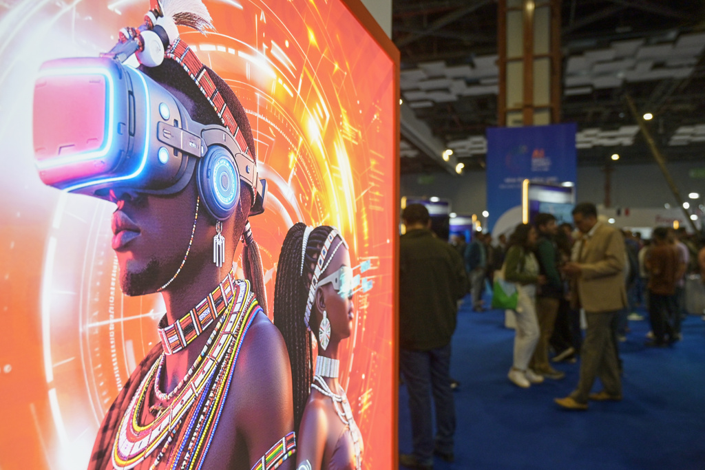 Visitors stand next to an advertising billboard at AI summit in New Delhi, India, Wednesday, Feb. 18, 2026. (AP Photo)