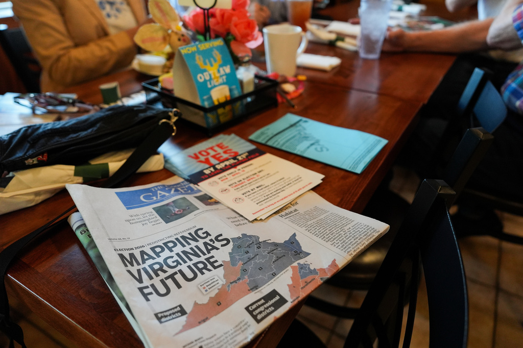 A print edition of the Goochland Gazette, with a front page story on the Virginia redistricting referendum, lies on a table at GG's Pizza as members of the Goochland Democratic Committee Jen Strozier, Doug Mock, Chris Svoboda, Richard Grebe and Judi Sheppard hold a lunch meeting on future get-out-the-vote efforts, Thursday, April 2, 2026, in Maiden, Va. (AP Photo/Julia Demaree Nikhinson)