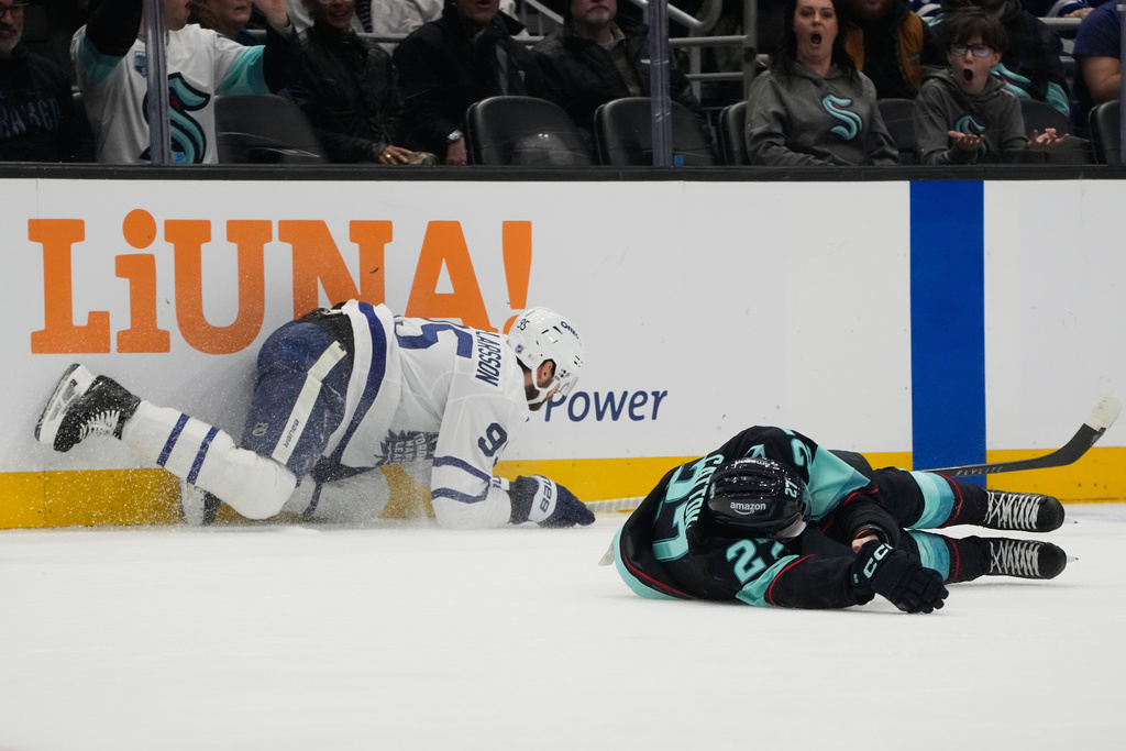 CORRECTS DATE - Seattle Kraken center Berkly Catton, right, falls against Toronto Maple Leafs defenseman Oliver Ekman-Larsson, left, during the first period of an NHL hockey game Thursday, Jan. 29, 2026, in Seattle. (AP Photo/Lindsey Wasson)