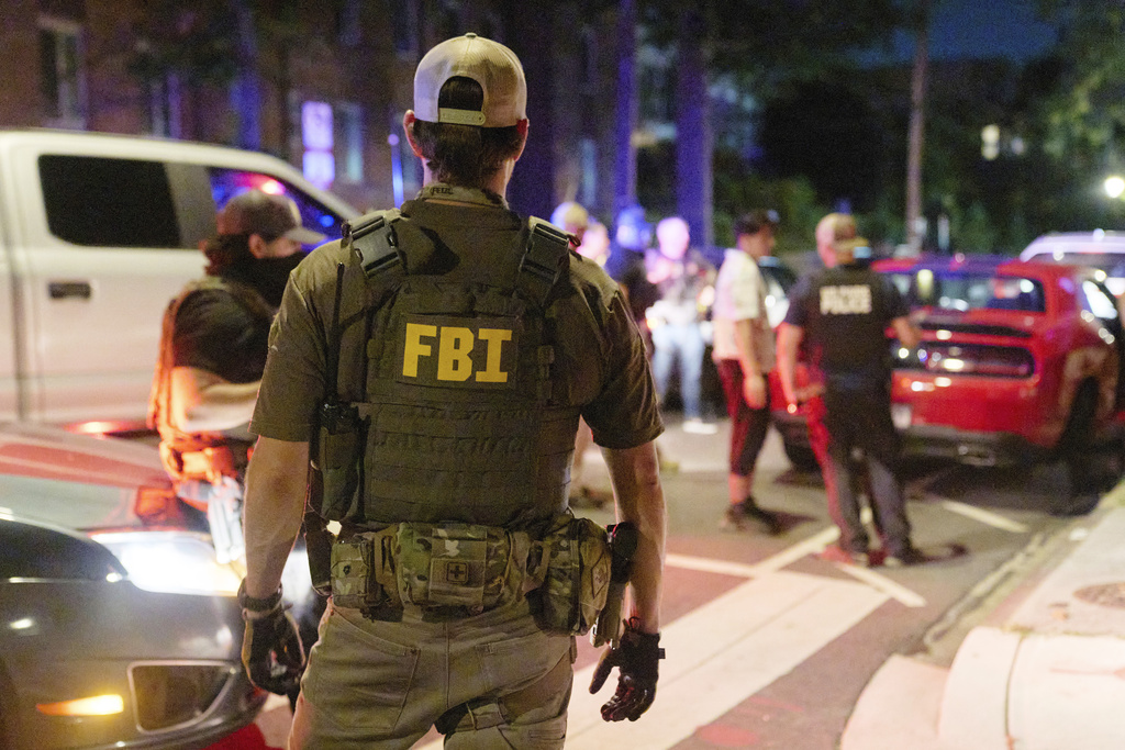Federal law enforcement agents from various agencies including Bureau of Alcohol, Tobacco, Firearms and Explosives, Park Police, and FBI, question a couple who had been parked outside a legal parking zone while eating McDonald's takeout, Tuesday, Aug. 12, 2025, in northwest Washington near Kennedy St. NW. The couple were released after a search of the car. (AP Photo/Jacquelyn Martin)