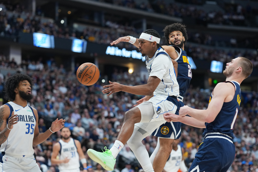 Dallas Mavericks guard Brandon Williams, center right, passes the ball to Dallas Mavericks forward Marvin Bagley III, left, while driving the lane past Denver Nuggets guards Jamal Murray, back right, and Christian Braun in the first half of an NBA basketball game Wednesday, March 25, 2026, in Denver. (AP Photo/David Zalubowski)
