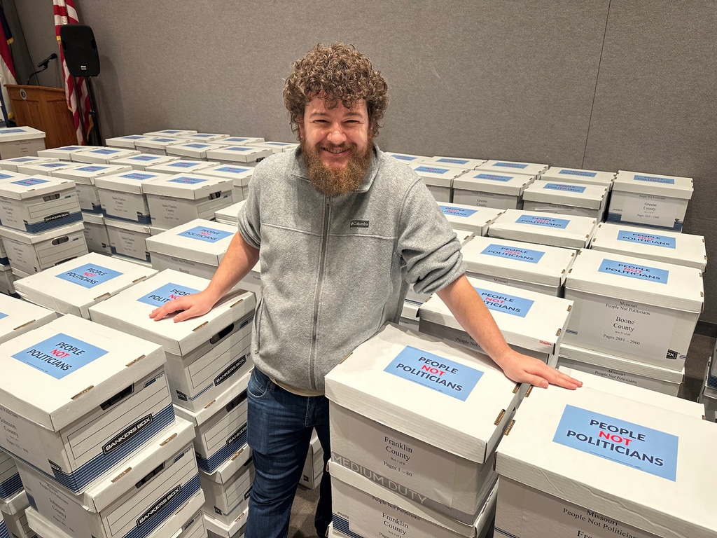 Lucas Kirk, of Sullivan, Mo., stands with boxes of petition signatures he helped collect and deliver on Tuesday, Dec. 9, 2025, to the secretary of state's office in Jefferson City, Mo., calling for a referendum election on new congressional districts approved by the state legislature. (AP Photo/David A. Lieb)