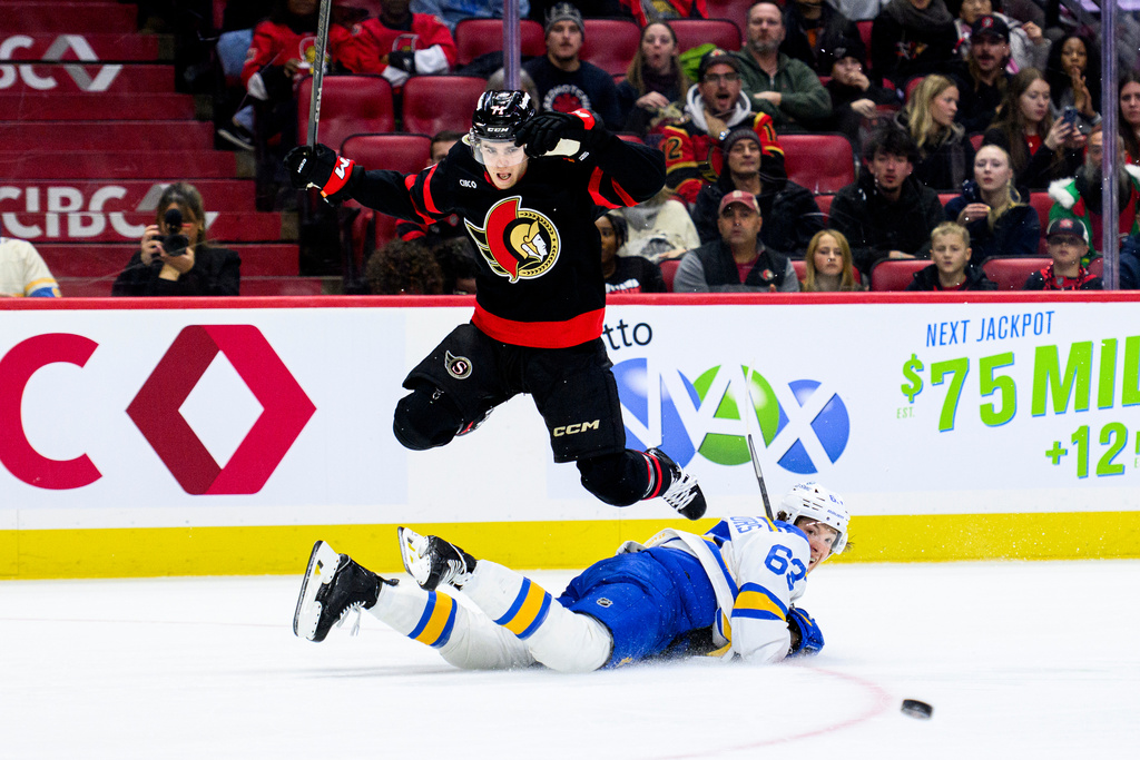 Ottawa Senators' Ridly Greig (71) leaps over St. Louis Blues' Jake Neighbours (63) as he makes a pass during second-period NHL hockey game action in Ottawa, Ontario, Saturday, Dec. 6, 2025. (Spencer Colby/The Canadian Press via AP)