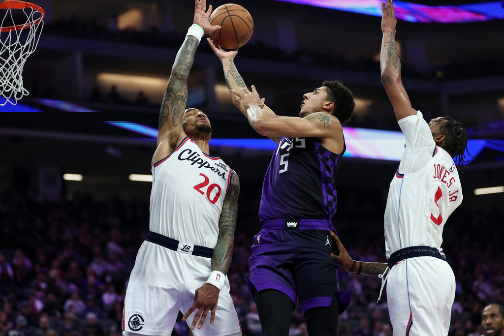 Sacramento Kings guard Nique Clifford, center, goes up to shoot between Los Angeles Clippers forwards John Collins (20) and Derrick Jones Jr., right, during the first half of an NBA basketball game Friday, Feb. 6, 2026, in Sacramento, Calif. (AP Photo/Sara Nevis)