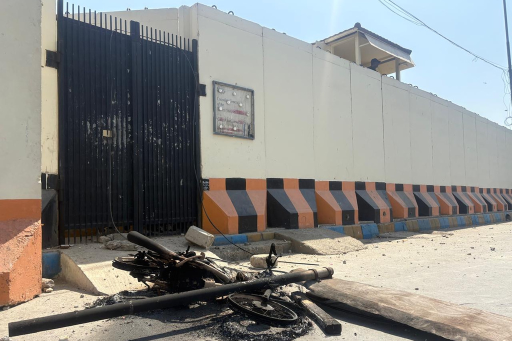 A security officer takes position as a motorcycle which was set on fire by angry protestors is seen outside the U.S. Consulate following protesters stormed the U.S. Consulate in Karachi, Pakistan, Sunday, March 1, 2026. (AP Photo/Muhammad Farooq)
