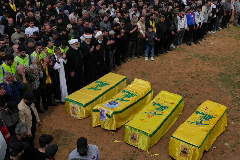 Mourners pray on the coffins of Hezbollah fighters and civilians who were killed in the war between Hezbollah and Israel during a mass funeral in Bazouriyeh village, south Lebanon, Monday, April 20, 2026. (AP Photo/Mohammed Zaatari)