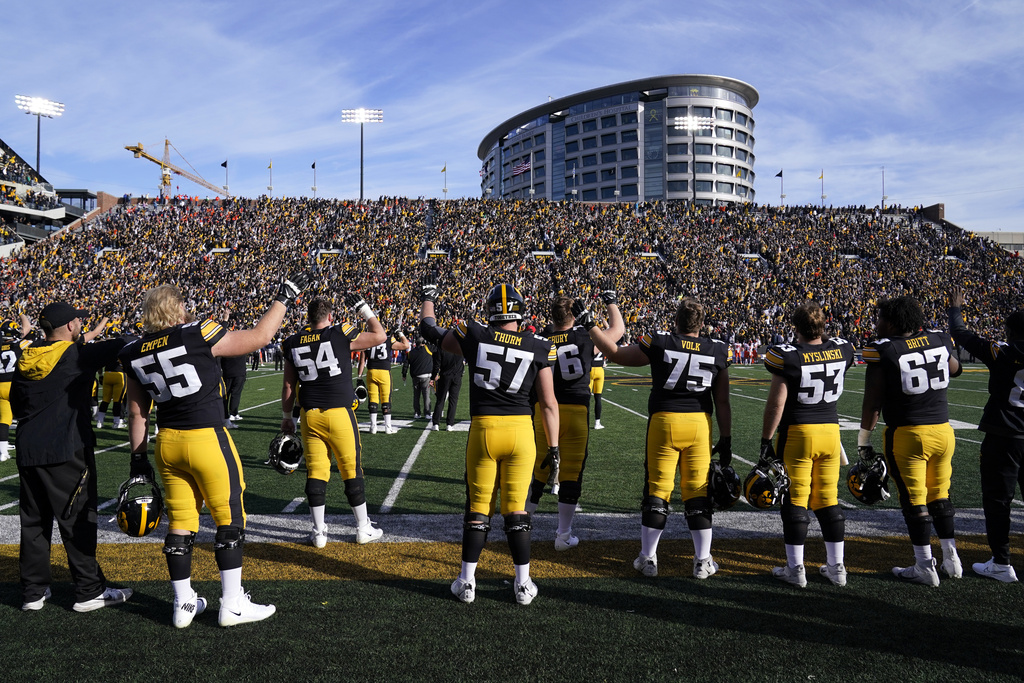 FILE - Iowa players wave to children in the University of Iowa Stead Family Children's Hospital, building in background, at the end of the first quarter of an NCAA college football game against Illinois, Saturday, Nov. 20, 2021, in Iowa City, Iowa. (AP Photo/Charlie Neibergall, File)