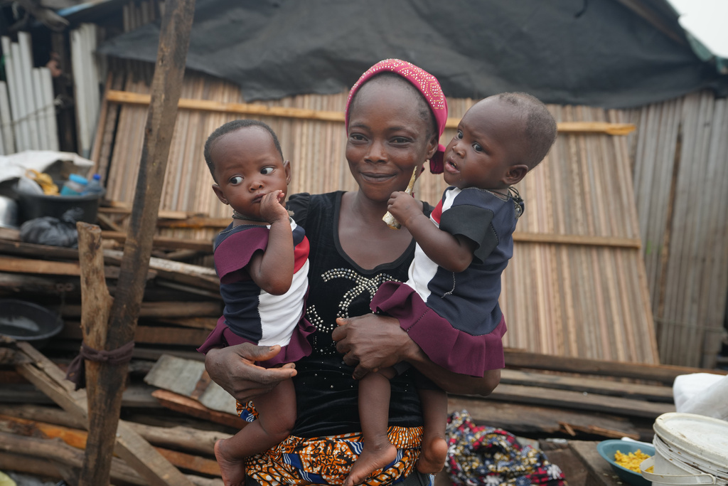 Josianua Agbokpasu poses with her twins at their demolished stilts house in Makoko Lagos, Nigeria, Friday, Jan.30, 2026. (AP Photo/Sunday Alamba)