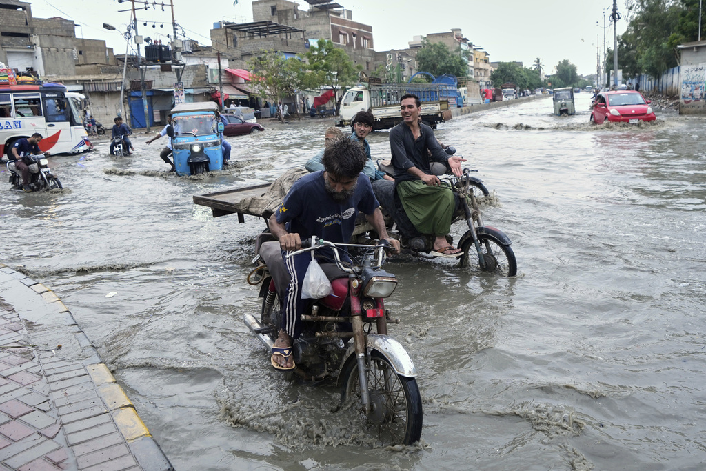 Motorcyclists navigate through a flooded road after heavy rainfall in Karachi, Pakistan, Tuesday, Aug. 19, 2025. (AP Photo/Fareed Khan)