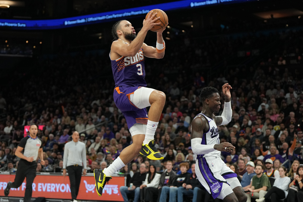 Phoenix Suns forward Dillon Brooks (3) goes up to shoot over Sacramento Kings guard Dennis Schroder, right, during the second half of an NBA basketball game, Friday, Jan. 2, 2026, in Phoenix. (AP Photo/Rick Scuteri)