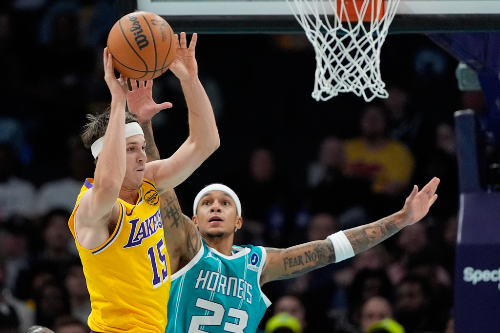 Los Angeles Lakers guard Austin Reaves passes around Charlotte Hornets guard Tre Mann during the first half of an NBA basketball game Monday, Nov. 10, 2025, in Charlotte, N.C. (AP Photo/Chris Carlson)