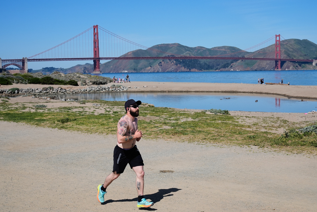 A man runs past at Crissy Field, backdropped by the Golden Gate Bridge in San Francisco, Tuesday, March 17, 2026. (AP Photo/Godofredo A. Vásquez)