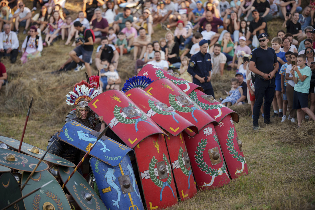 People watch as members of historical reenactment groups wearing Roman soldier outfits, demonstrate Roman era warfare tactics in Poiana, Romania, Saturday, July 12, 2025, during the Getodava historical reenactment festival. (AP Photo/Vadim Ghirda)