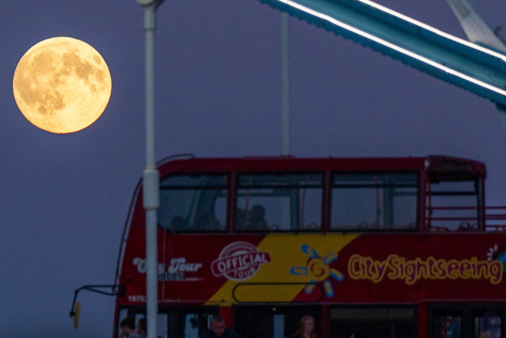 The Harvest Supermoon rises as a red double-decker bus drives past on Tower Bridge, Monday, Oct. 6, 2025, in London. (AP Photo/Julia Demaree Nikhinson)