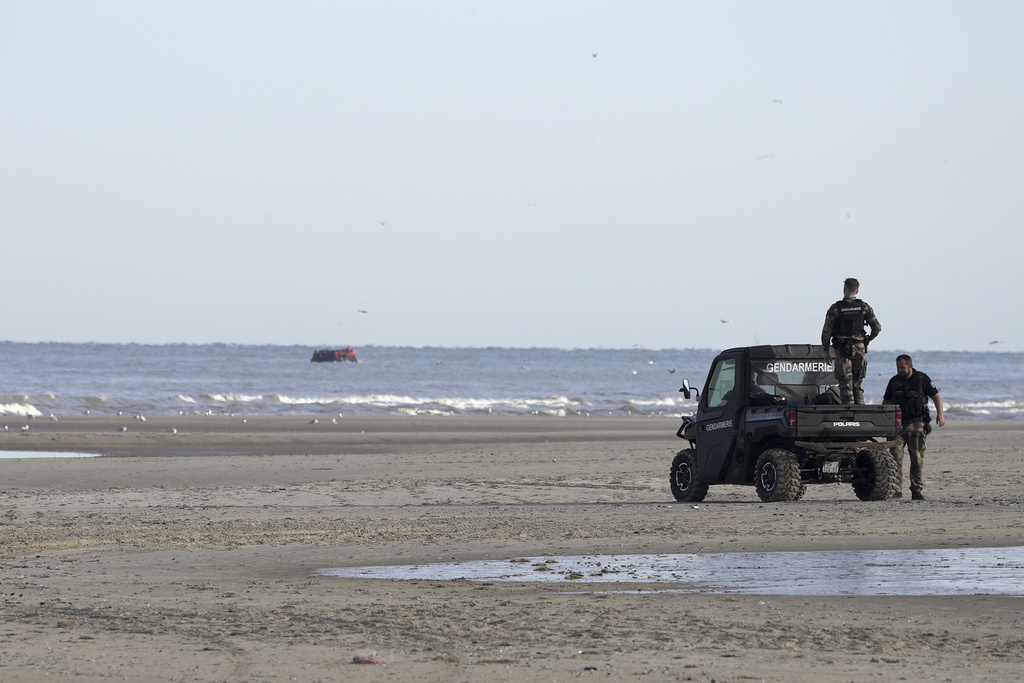 FILE - Gendarmes watch migrants on a small boat from Ecault beach, Friday July 4, 2025. (AP photo/John Leicester, File)