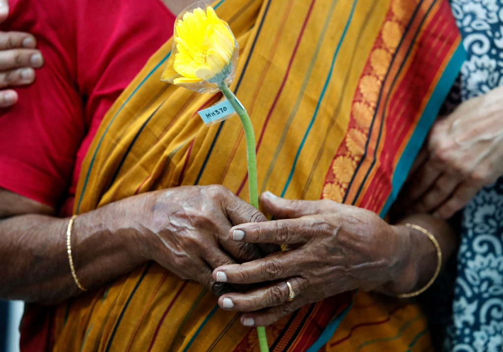 FILE - A family member of passengers on board of the missing Malaysia Airlines Flight 370 holds a flower during the tenth annual remembrance event at a shopping mall, in Subang Jaya, on the outskirts of Kuala Lumpur, Malaysia, March 3, 2024. (AP Photo/FL Wong, File)