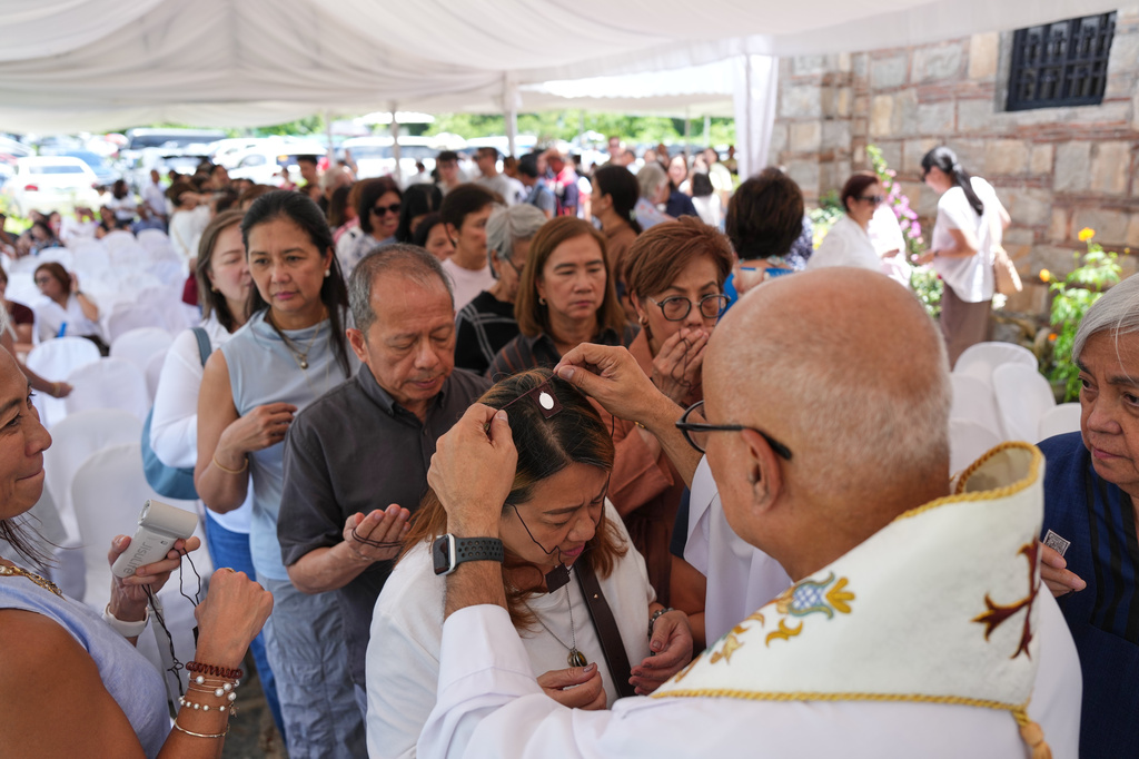 Catholic priest Father Dennis Paez places a scapular necklace on pilgrims during their visit at the Ephesus House, a replica of the House of the Virgin Mary in Ephesus, Turkey, at Alfonso town, Cavite province, Philippines on July 16, 2026. (AP Photo/Aaron Favila)
