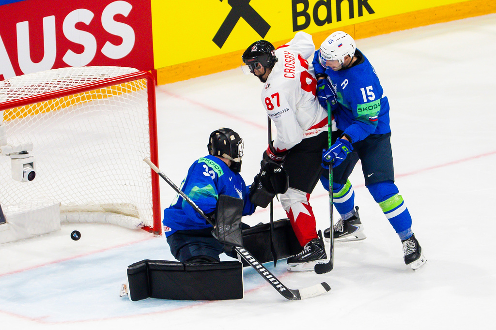 Slovenia's goaltender Zan Us, left, concedes his second goal past Slovenia's Blaz Gregorc, right, and Canada's Sidney Crosby, center, during a preliminary round game between Canada and Slovenia at the men's ice hockey world championship in Fribourg, Switzerland, Friday May 22, 2026. (Salvatore Di Nolfi/Keystone via AP)