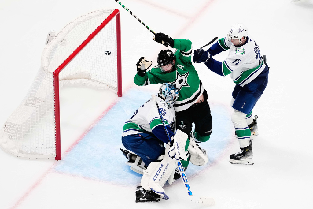 Dallas Stars center Tyler Seguin (91) pressures the net as Vancouver Canucks' Thatcher Demko (35) and Filip Chytil (72) defend against a shot in the third period of an NHL hockey game Thursday, Oct. 16, 2025, in Dallas. (AP Photo/Tony Gutierrez)