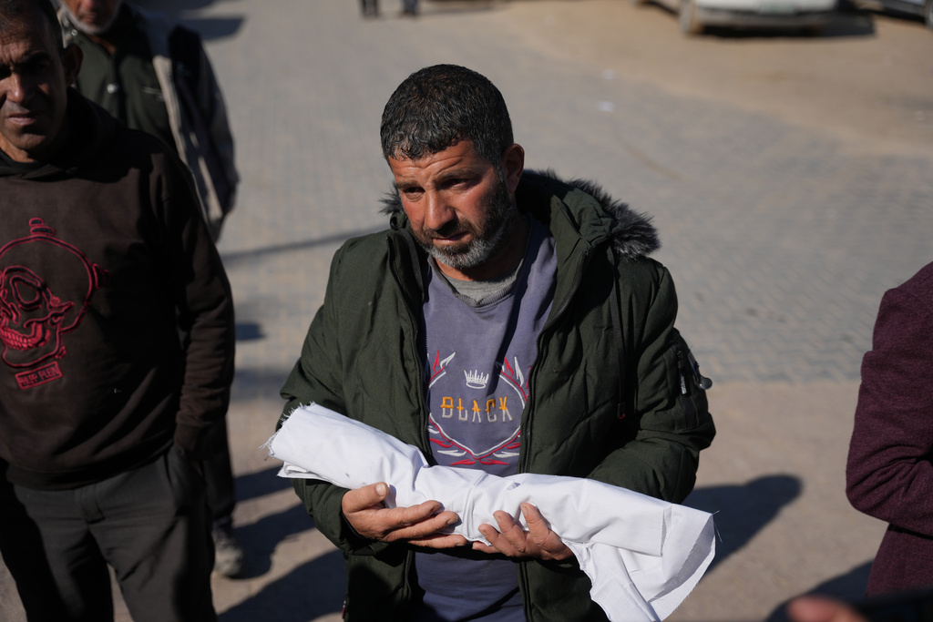 Eseid Abdeen, 42, carries the body of his 29-day-old infant son, Saeed, who, according to health authorities, died due to the cold weather, as he stands outside Nasser Hospital in Khan Younis, southern Gaza Strip, Thursday, Dec. 18, 2025. (AP Photo/Abdel Kareem Hana)