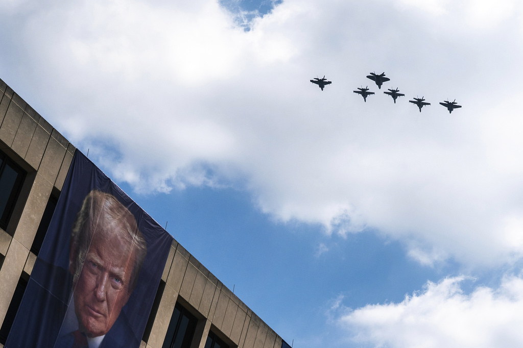 A flight of F-18s, F-35s and a F-22 fly past a picture of President Donald Trump hanging on the U.S. Department of Labor near the Great American State Fair on the National Mall, Friday, July 3, 2026, in Washington. (AP Photo/Nathan Howard)