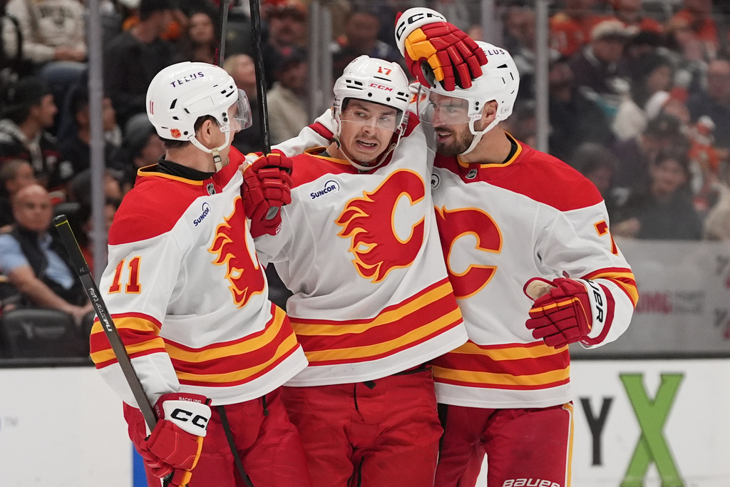 Calgary Flames center Yegor Sharangovich, center, celebrates his goal with teammates center Mikael Backlund (11) and defenseman Kevin Bahl, right, during the second period of an NHL hockey game against the Anaheim Ducks Sunday, March 1, 2026, in Anaheim, Calif. (AP Photo/Gregory Bull)