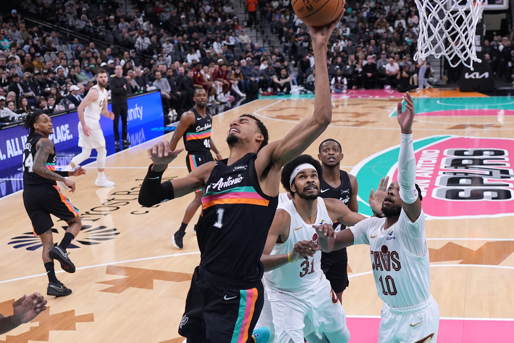 San Antonio Spurs forward Victor Wembanyama (1) is fouled as he tries to score past Cleveland Cavaliers center Jarrett Allen (31) and guard Darius Garland (10) during the second half of an NBA basketball game in San Antonio, Monday, Dec. 29, 2025. (AP Photo/Eric Gay)