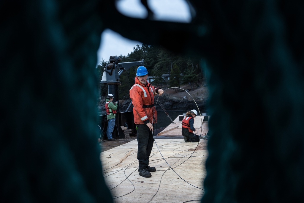 Tor Bjorklund, an oceanographer with the University of Washington, unwinds a fiber-optic cable on a barge before deploying it to the seafloor to listen for endangered orcas near San Juan Island, Wash., Friday, Oct. 10, 2025. (AP Photo/Annika Hammerschlag)