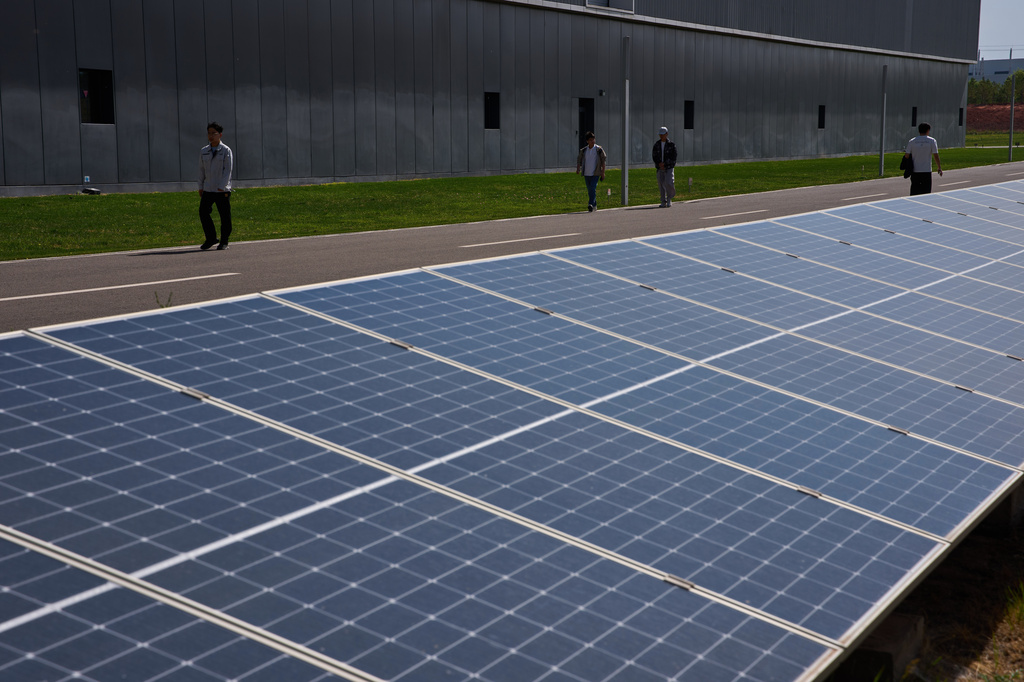 Workers walk by solar panels in the Envision Ordos Modern Energy Equipment Industrial Park in Ordos in northern China's Inner Mongolia province on Friday, June 12, 2026. (AP Photo/Ng Han Guan)