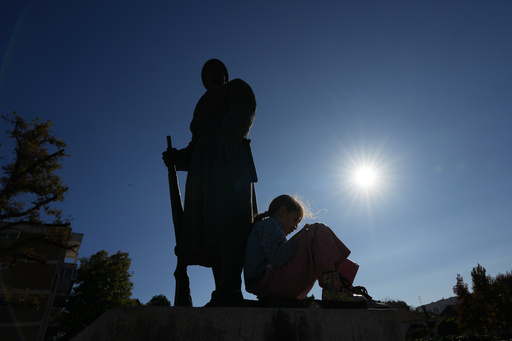 A girl sits on a monument dedicated to Serbian warriors as she waits for students during a march towards the northern city of Novi Sad, for a rally on Nov. 1 marking the first anniversary of a train station disaster that killed 16 people, in Ub, Serbia, Monday, Oct. 27, 2025. (AP Photo/Darko Vojinovic) A girl sits on a monument dedicated to Serbian warriors as she waits for students during a march towards the northern city of Novi Sad, for a rally on Nov. 1 marking the first anniversary of a train station disaster that killed 16 people, in Ub, Serbia, Monday, Oct. 27, 2025. (AP Photo/Darko Vojinovic)