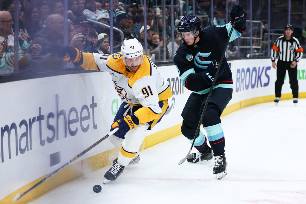 Nashville Predators center Steven Stamkos (91) and Seattle Kraken defenseman Cale Fleury, right, battle for a loose puck in the second period during an NHL hockey game Thursday, Jan. 1, 2026, in Seattle. (AP Photo/Kevin Ng)