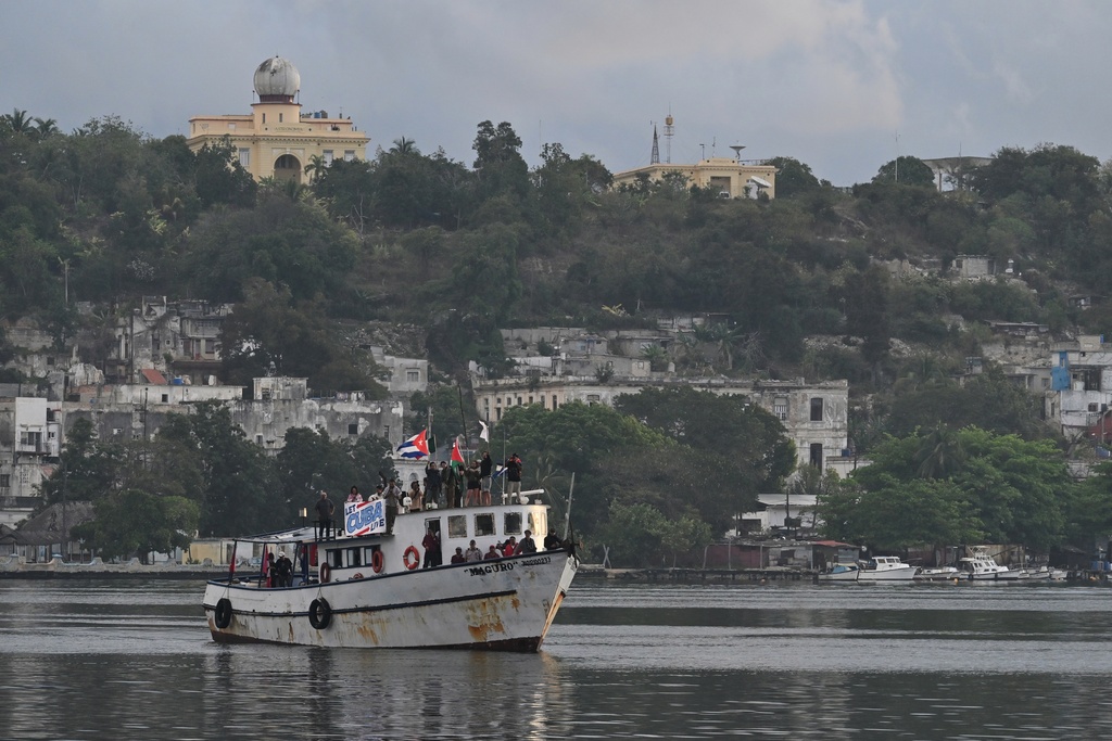 Activists wave Cuban and Palestinian flags from the vessel Maguro, arriving from Mexico with humanitarian aid as part of the "Nuestra America," or Our America convoy, in Havana Bay, Cuba, Tuesday, March 24, 2026. (AP Photo/Jorge Luis Banos)