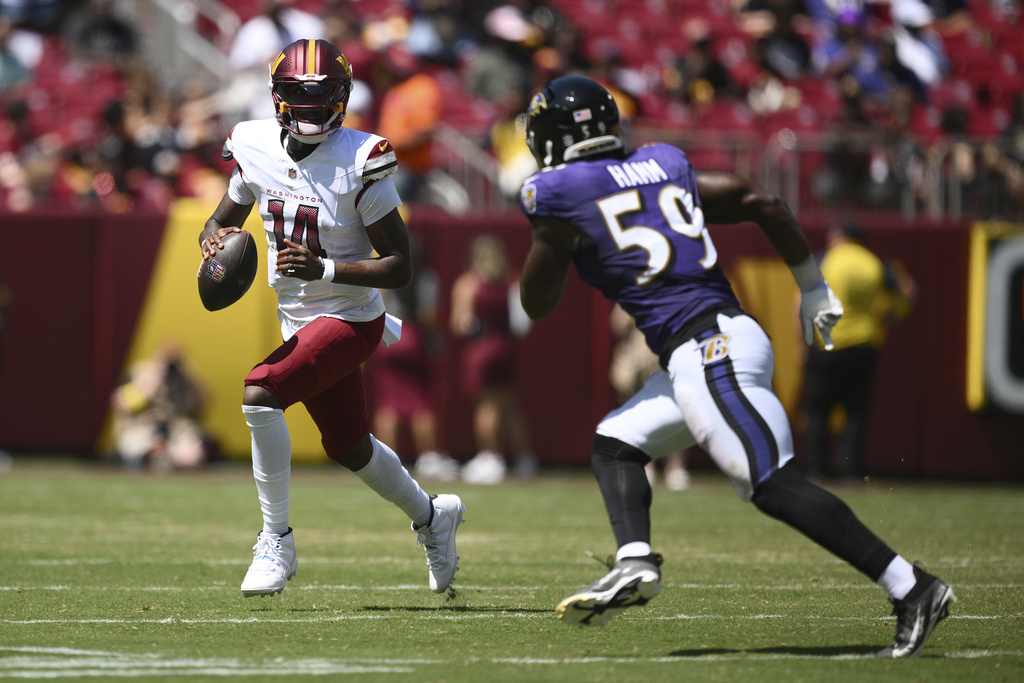 Washington Commanders quarterback Josh Johnson (14) scrambles as Baltimore Ravens outside linebacker Malik Hamm (59) defends during the second half of a preseason NFL football game Saturday, Aug. 23, 2025, in Landover, Md. (AP Photo/Nick Wass)