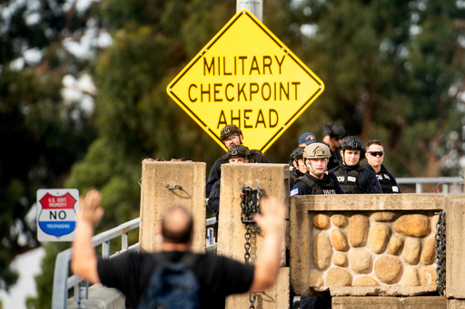 Coast Guardsmen stand watch behind a barrier at Coast Guard Base Alameda as an anti-ICE protester approaches on Friday, Oct. 24, 2025, in Oakland, Calif. The barrier was erected earlier in the day after law enforcement officers fired on a vehicle as it backed towards them. (AP Photo/Noah Berger) Coast Guardsmen stand watch behind a barrier at Coast Guard Base Alameda as an anti-ICE protester approaches on Friday, Oct. 24, 2025, in Oakland, Calif. The barrier was erected earlier in the day after law enforcement officers fired on a vehicle as it backed towards them. (AP Photo/Noah Berger)
