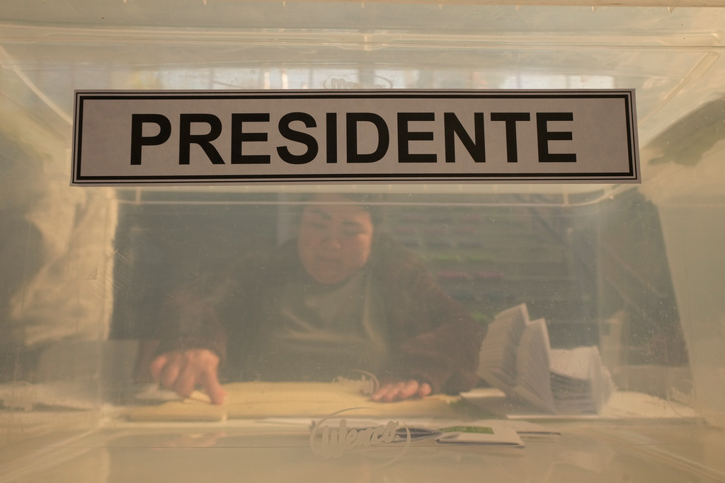An electoral worker sits behind the ballot box at a polling station during general elections in Santiago, Chile, Sunday, Nov. 16, 2025. (AP Photo/Esteban Felix)