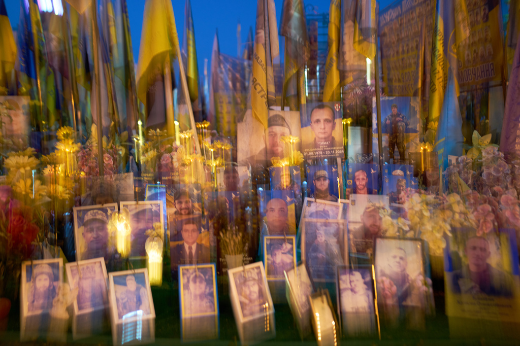 In this slow shutter speed photo, Ukrainian flags and photographs are displayed in memory of civilians and soldiers killed during the war with Russia in central Kyiv, Friday, Aug. 21, 2026. (AP Photo/Francisco Seco)