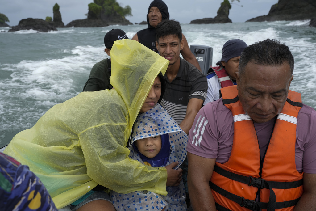 Venezuelan Mariela Gomez holds her son Mathias as they boat to shore after arriving on a larger cargo vessel in Jaque, on Panama's Pacific coast, Thursday, Sept. 18, 2025, during their journey south after giving up on reaching the United States. (AP Photo/Matias Delacroix)