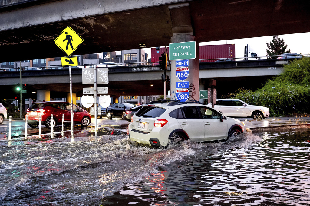A car traverses a flooded freeway ramp on Monday, Oct. 13, 2025, in Oakland, Calif. (AP Photo/Noah Berger)