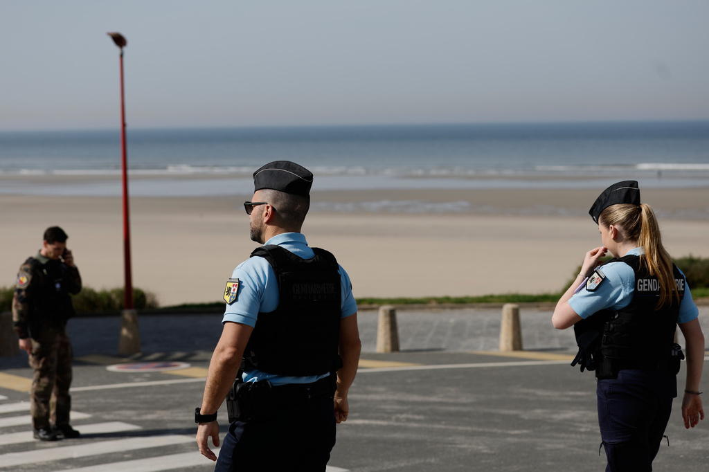 Policemen stand guard after a migrant taxi-boat accident, in Equihen-Plage, northern France, Thursday, April 9, 2026. (AP Photo/Jean-Francois Badias)