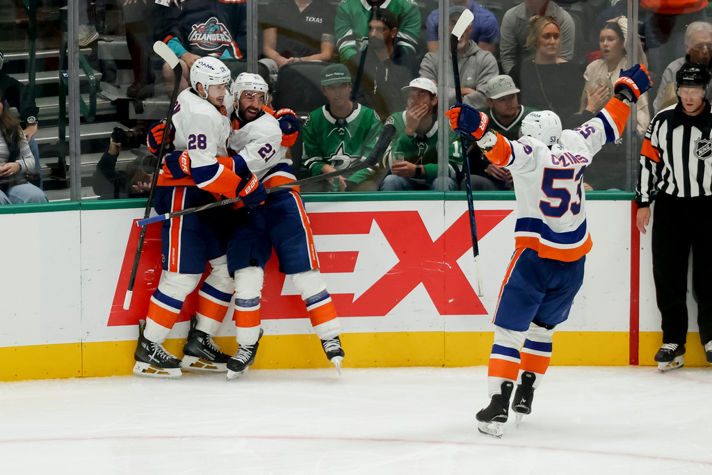 New York Islanders defenseman Alexander Romanov (28) and center Casey Cizikas (53) celebrate a goal by center Kyle Palmieri (21) during the third period of an NHL hockey game against the Dallas Stars, Tuesday, Nov. 18, 2025, in Dallas. (AP Photo/Gareth Patterson)