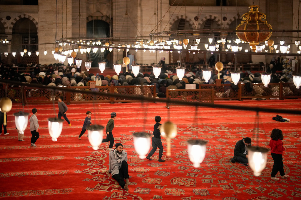 A worshipper rests as others perform the night prayer known as "Tarawih" on the eve of the first day of the Muslim holy month of Ramadan at the Suleymaniye Mosque in Istanbul, Wednesday, Feb. 18, 2026. (AP Photo/Emrah Gurel)