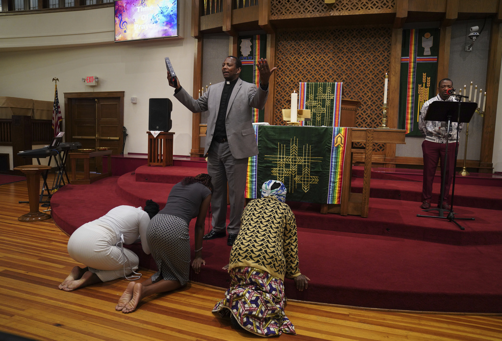 The Rev. Daniel Niyonzima, a refugee from Burundi who arrived in the United States with his wife 20 years ago, prays with congregants in Kirundi, one of Burundi's languages, during service at St. Paul's United Methodist Church on Sunday, Aug. 10, 2025, in Cedar Rapids, Iowa. (AP Photo/Jessie Wardarski)