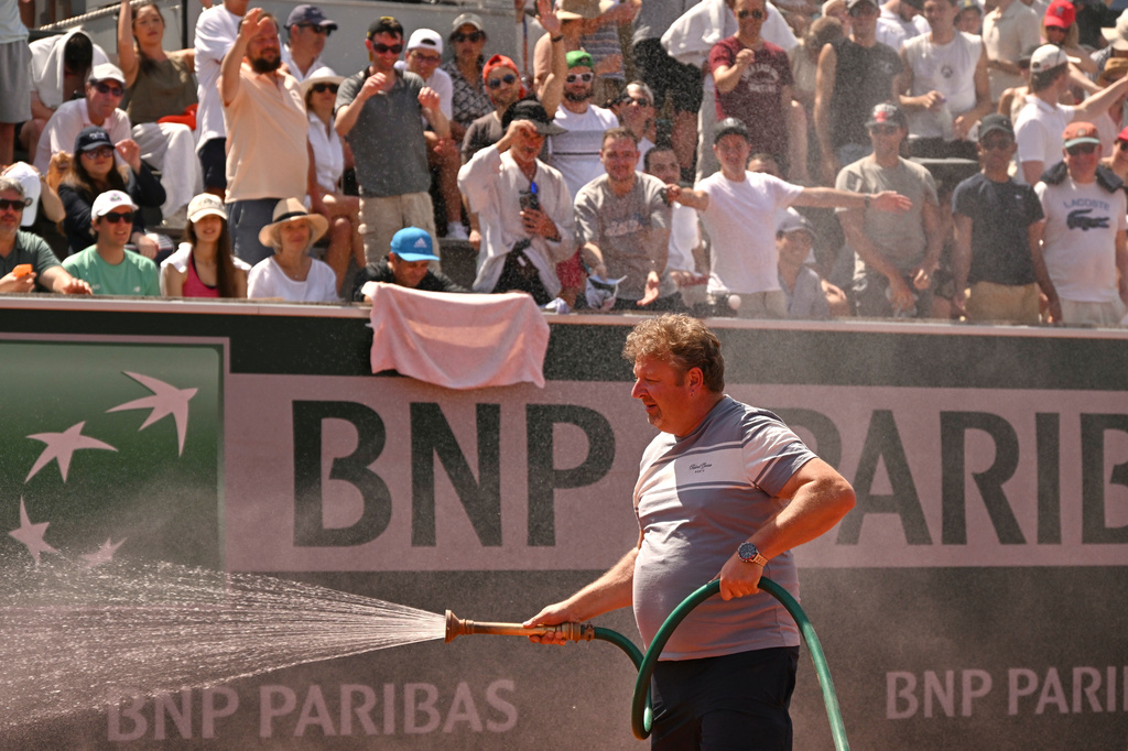 Spectators react as stadium worker sprays the court with water during the second round men's singles tennis match between Hubert Hurkacz of Poland and Frances Tiafoe of the U.S at the French Open tennis tournament in Paris, Thursday, May 28, 2026. (AP Photo/Emma Da Silva)
