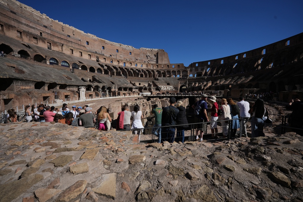 Visitors admire the Colosseum where the so-called 'Passage of Emperor Commodus', a newly restored tunnel ancient Roman emperors would use to enter the Colosseum unseen and protected will open to visitors at the end of the month, in Rome, Wednesday, Oct. 8, 2025. (AP Photo/Andrew Medichini)