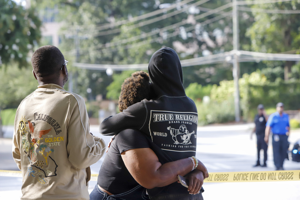 Pedestrians comfort each other after a shooting near the campuses of the U.S. Centers for Disease Control and Prevention and Emory University, Friday, Aug. 8, 2025, in Atlanta. (Jenni Girtman/Atlanta Journal-Constitution via AP)