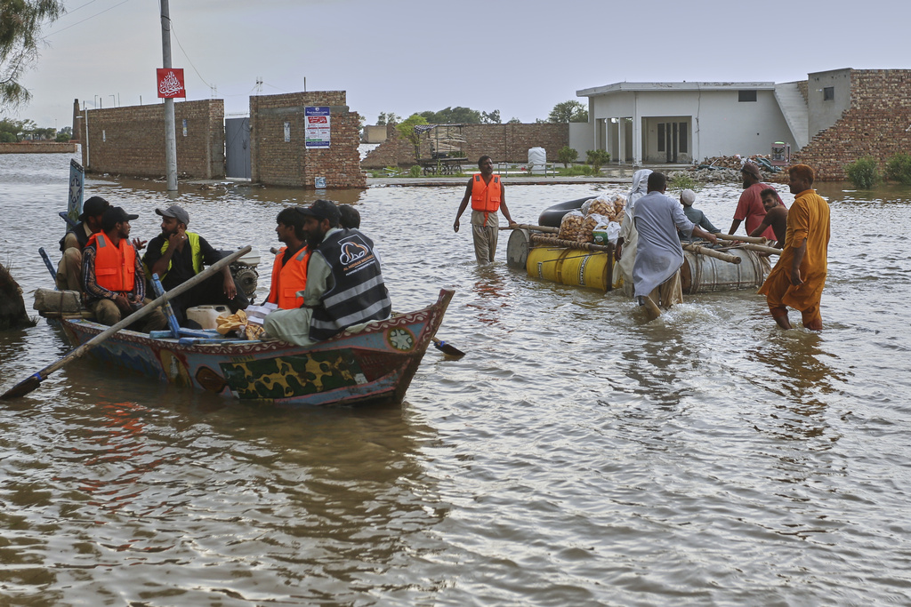 A rescue boat move past villagers pushing a makeshift raft following raising water level in rivers, in Jalalpur Pirwala, in Multan district, Pakistan, Monday, Sept. 8, 2025. (AP Photo/Asim Tanveer)