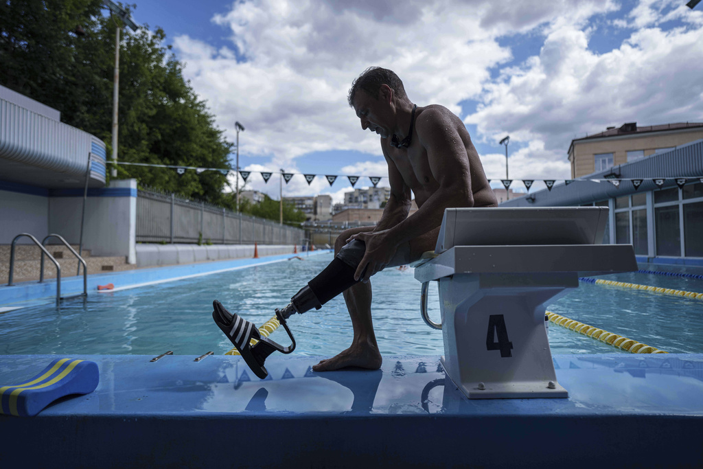 Ukrainian war veteran Pavlo Tovstyk removes his prosthesis in Kyiv, Ukraine, Tuesday, Aug. 12, 2025, as he prepares to train for an upcoming 6.5km swimming race across the Bosporus Strait. (AP Photo/Evgeniy Maloletka)