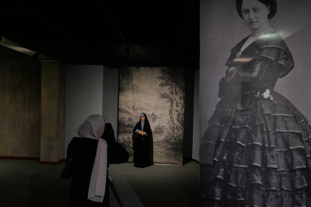 A woman poses for a photo while visiting a photography exhibit showcasing works by international photographers from the collection of the Tehran Museum of Contemporary Art, in Tehran, Saturday, Aug. 22, 2026. (AP Photo/Vahid Salemi)