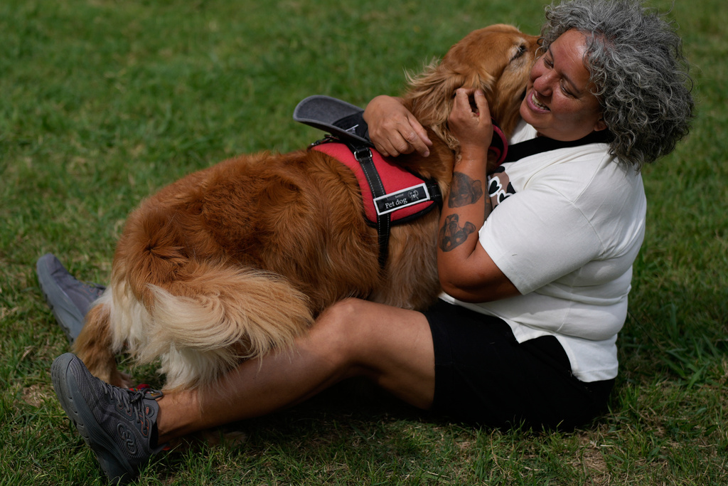 A woman hugs her dog at a Palermo neighborhood park as people try to set a world record of most Golden Retrievers gathered in a park, in Buenos Aires, Argentina, Monday, Dec. 8, 2025. (AP Photo/Natacha Pisarenko)
